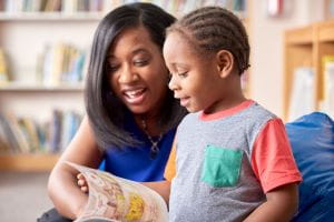 An image of a community engagement specialist reading to a child.